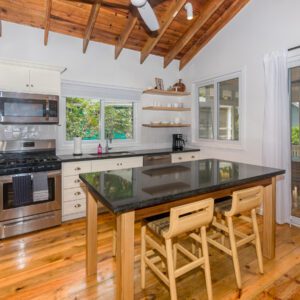 A kitchen with wooden floors and black counter tops.