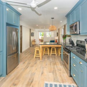 A kitchen with blue cabinets and wood floors.