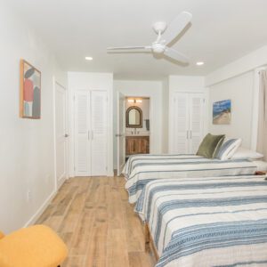 A bedroom with two beds and a fan in the ceiling.