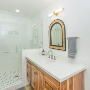 A bathroom with a sink, mirror and shower.