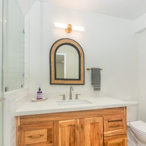 A bathroom with a sink, mirror and toilet.