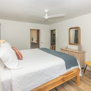 A bedroom with a bed, dresser and mirror.