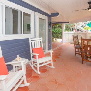 A porch with two rocking chairs and tables.