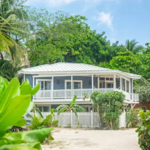 A house with a white fence and palm trees in the background.