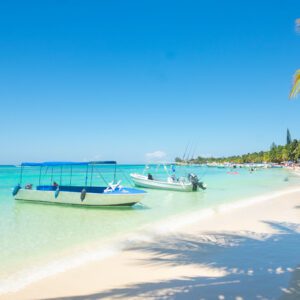 A beach with boats floating in the water.