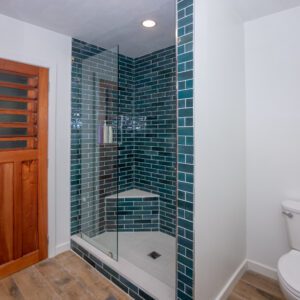 A bathroom with blue tile and wood floors.